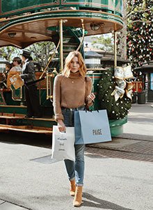 Woman holding shopping bags while standing in front of a decorated trolley at The Grove